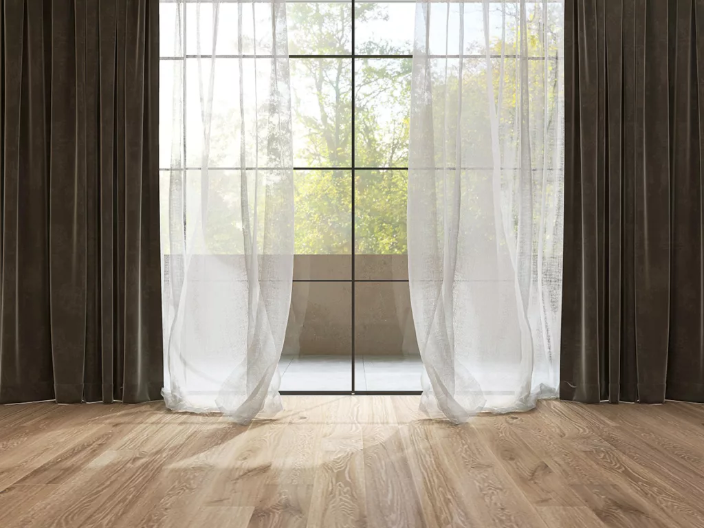 Two layers of white sheer curtain and dark brown blackout curtains, covering a window to keep the electric bill low in the summer