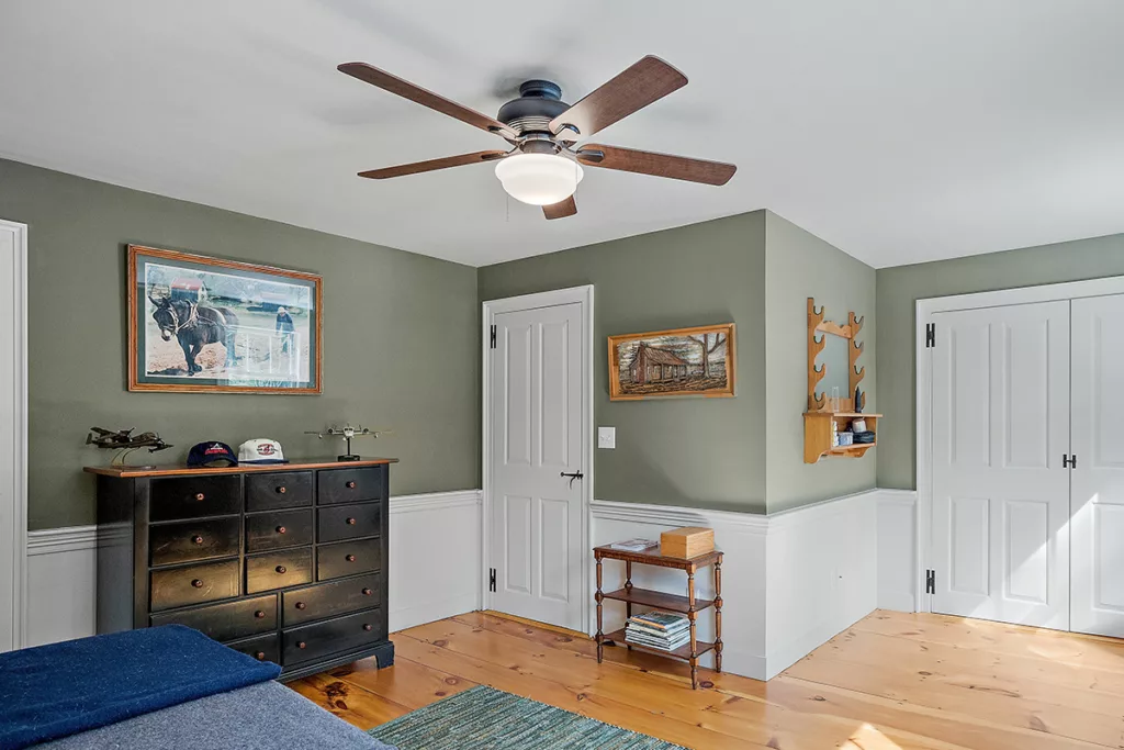 A ceiling fan in a bright bedroom with hardwood floors