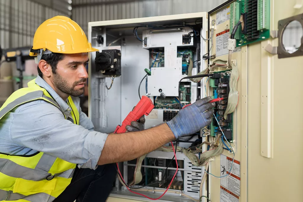 An electrician investigates a control panel during a commercial electrical inspection.