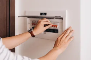 A close-up of someone's hands as they check an outdated circuit breaker, showing the concept of the dangers of an outdated electrical system.